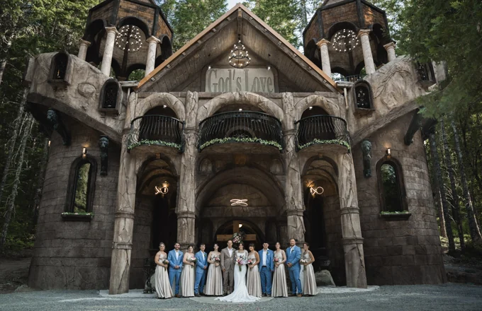 Wedding party gathered in front of the cathedral chapel surrounded by trees