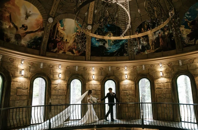 Newlyweds walking along the chapel balcony beneath a painted dome and chandelier