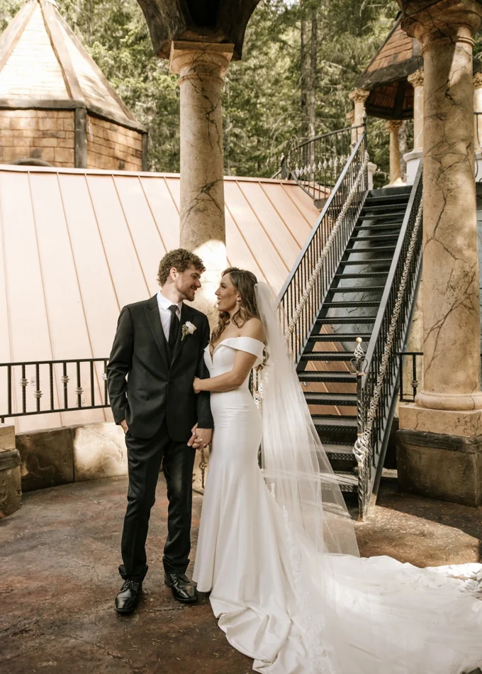Newlyweds standing beside the chapel staircase and stone columns