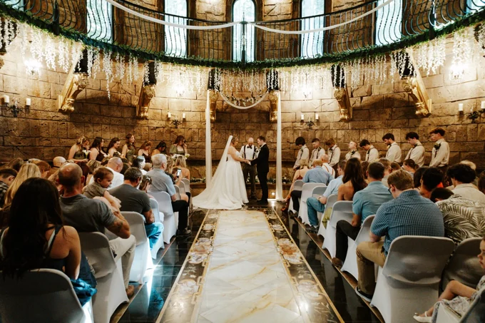 Wedding ceremony viewed down the chapel aisle with guests seated on both sides