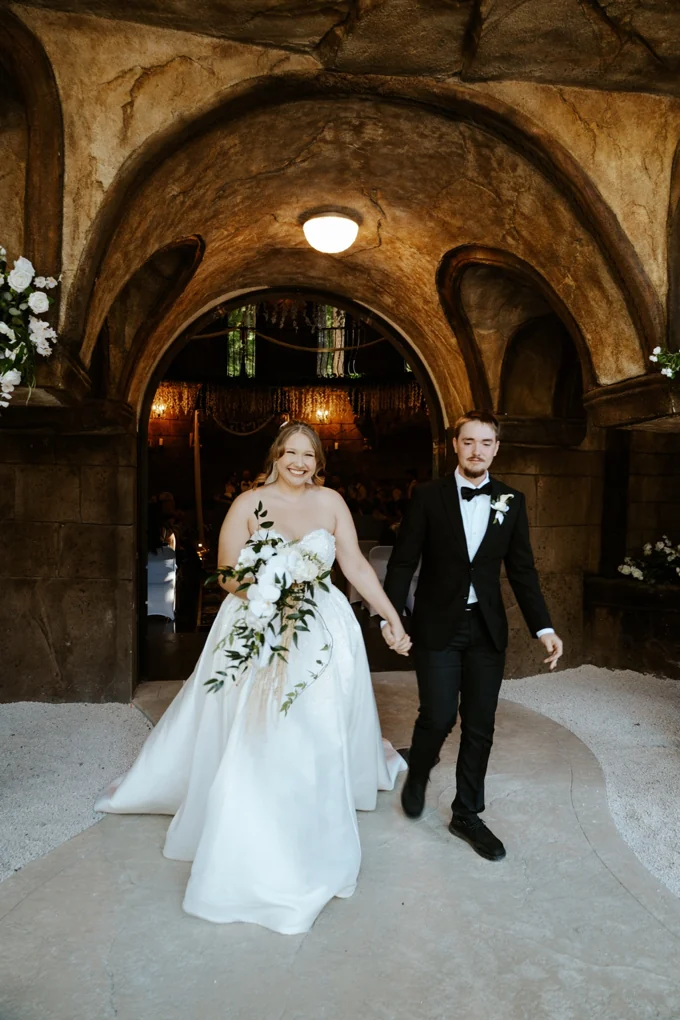 Newlyweds walking hand in hand through the arched chapel doorway