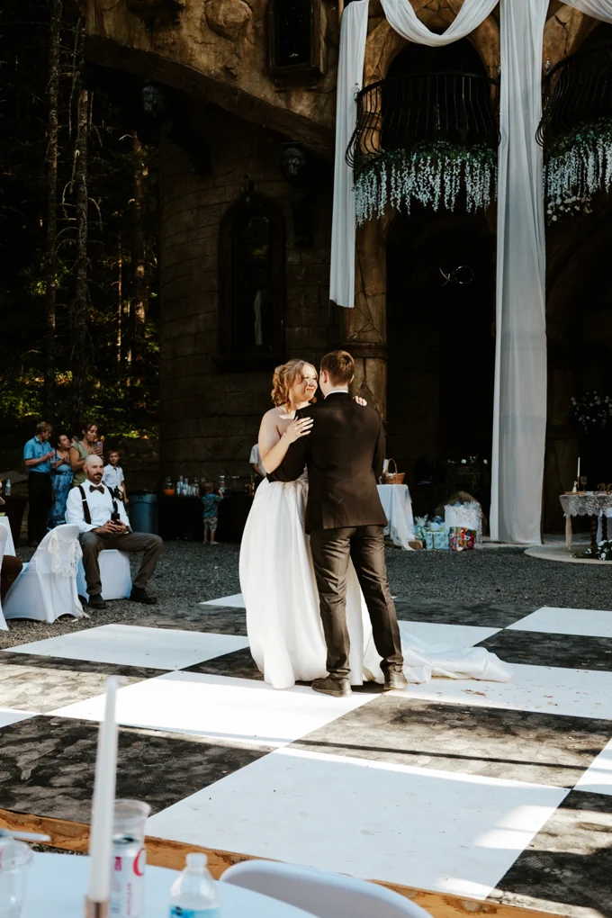 Newlyweds sharing a first dance on a checkered floor outside the chapel