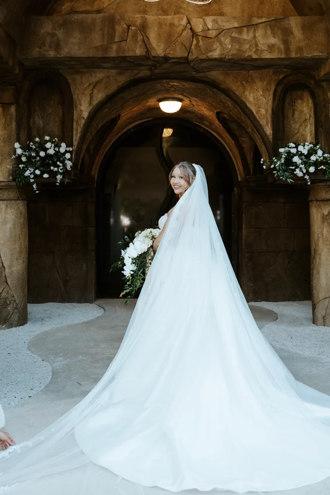 Bride with a flowing veil at the stone chapel entrance