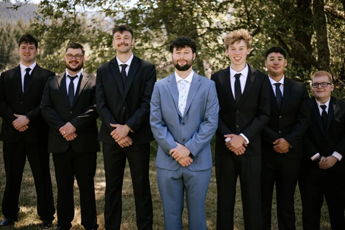 Groom and wedding party standing together outdoors